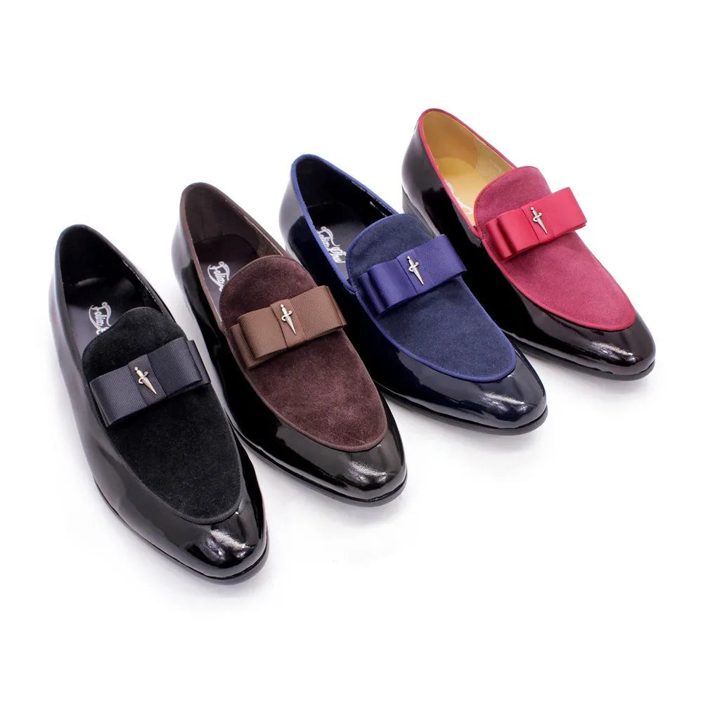 Men's black and brown tassel loafers with a matte and patent leather upper on a wooden floor.