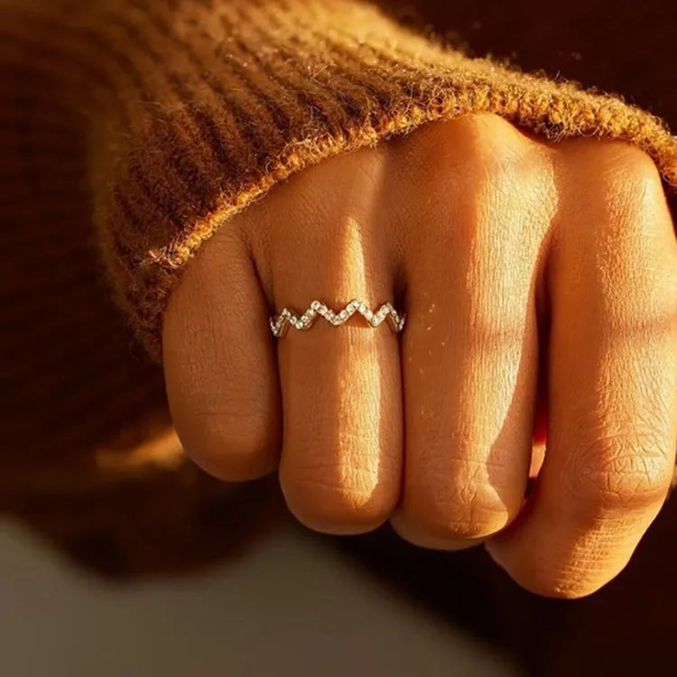 Sterling silver wave pattern adjustable ring with gem inlay, gold colour, against neutral background