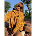Dopamine yellow and black plaid shirt with a loose cardigan style fit on a hanger.