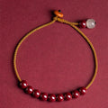 Hand-woven cinnabar and Hetian jade geometric bracelet on wrist showing natural stone textures