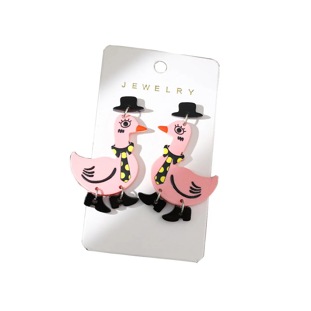 Three pairs of acrylic cartoon duck earrings in pink, white, and yellow on a light background