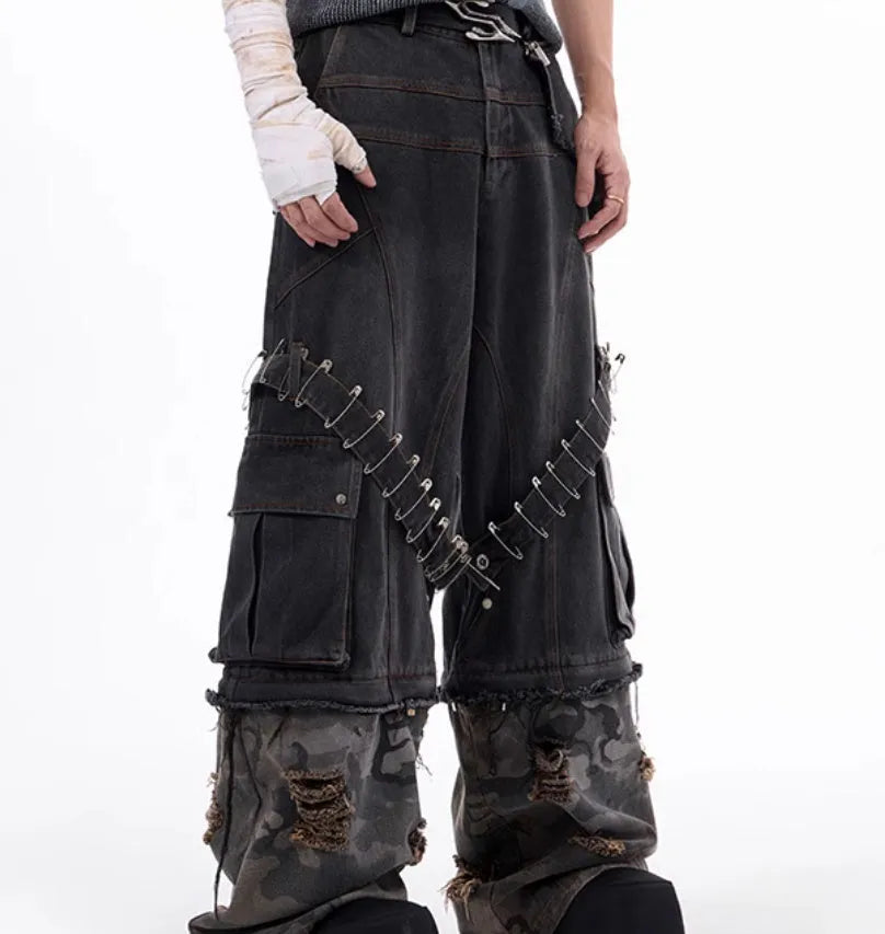 Men's grey jeans with camouflage splicing design and pin and ribbon details on the legs.
