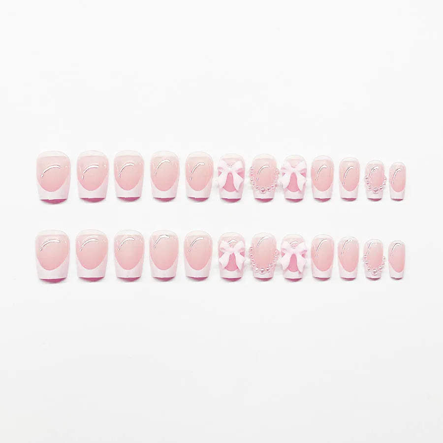 Short white French tip press-on nails with a cute pink bow design and a tulip pattern on a blush base.
