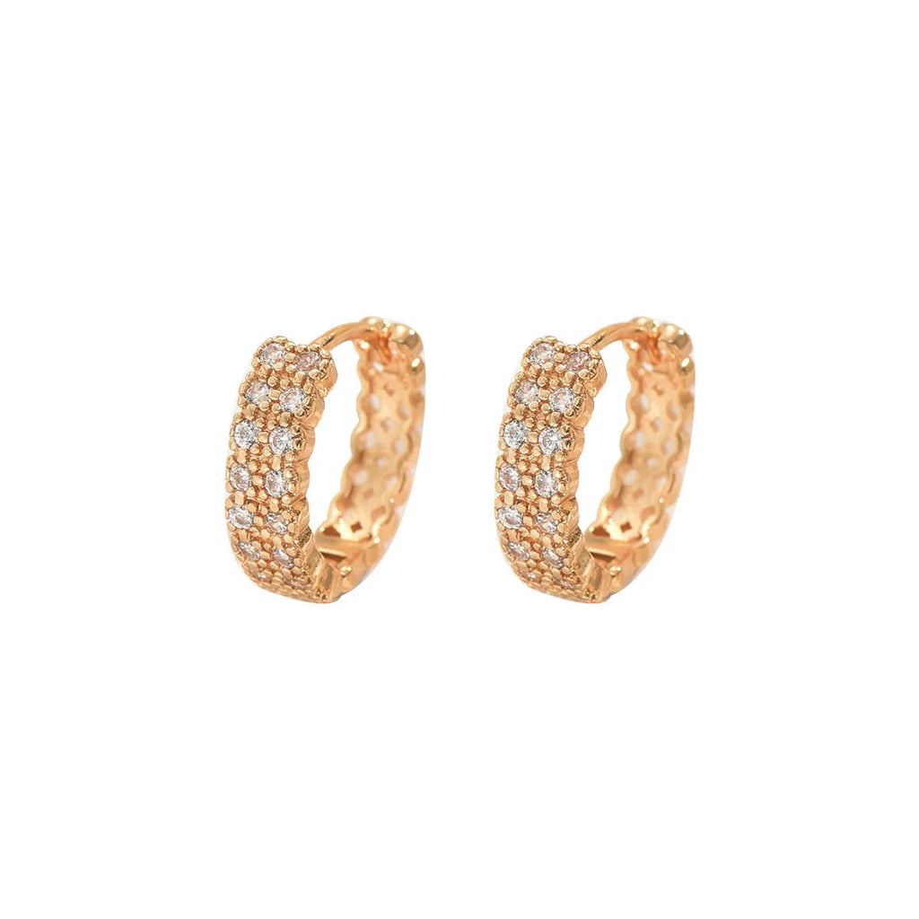 Close-up of geometric copper ear studs showing a ring with a central dot, on a plain background.