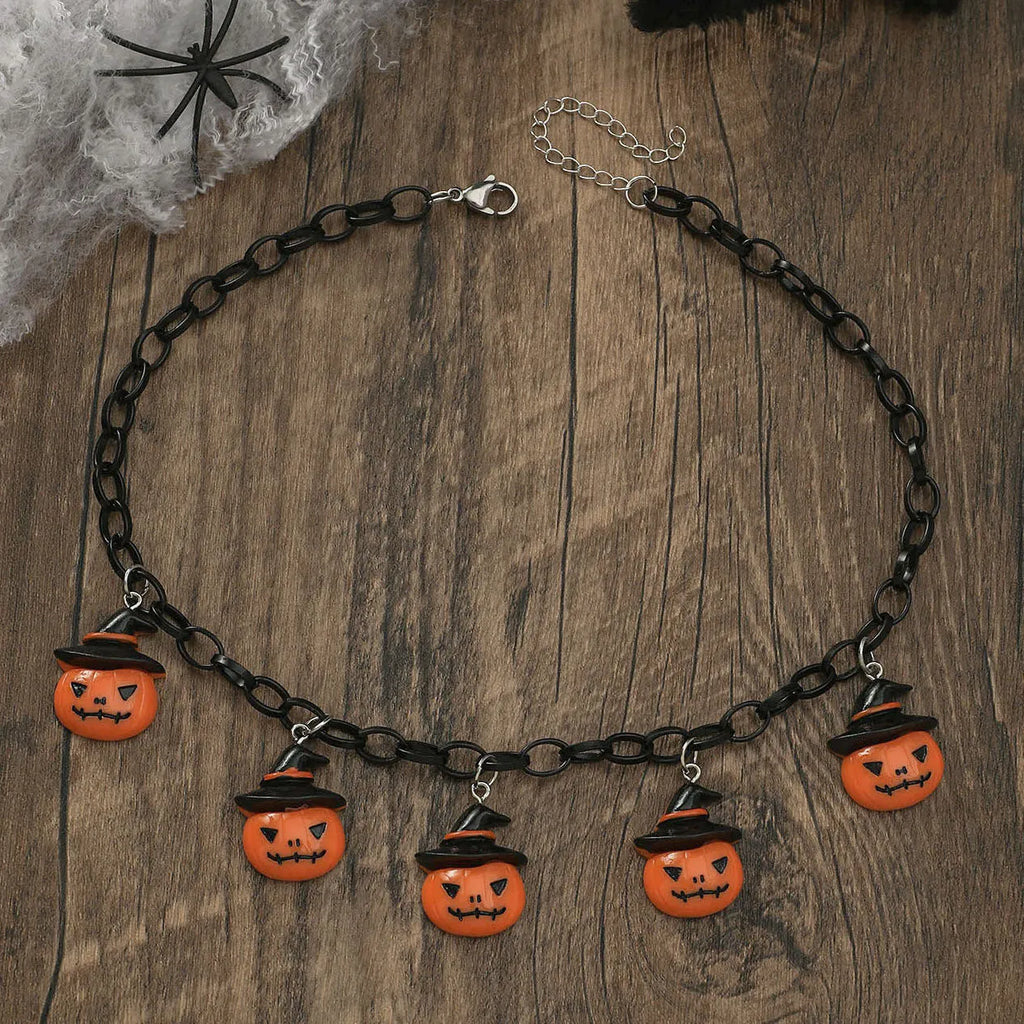 A Halloween necklace with an acrylic pumpkin and skull pendant on a clavicle chain