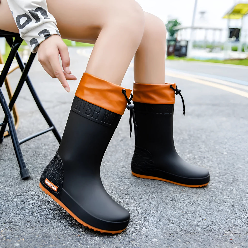 Women's solid colour PVC rain boot with non-slip sole in apricot, black, brown, or pink.