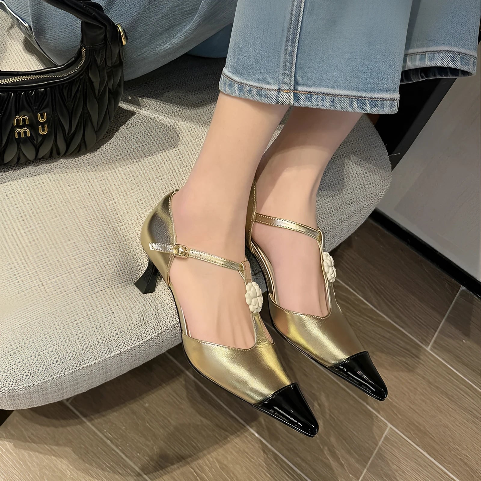 Women's gold stiletto shoe with flower decoration and buckle on sheepskin upper.