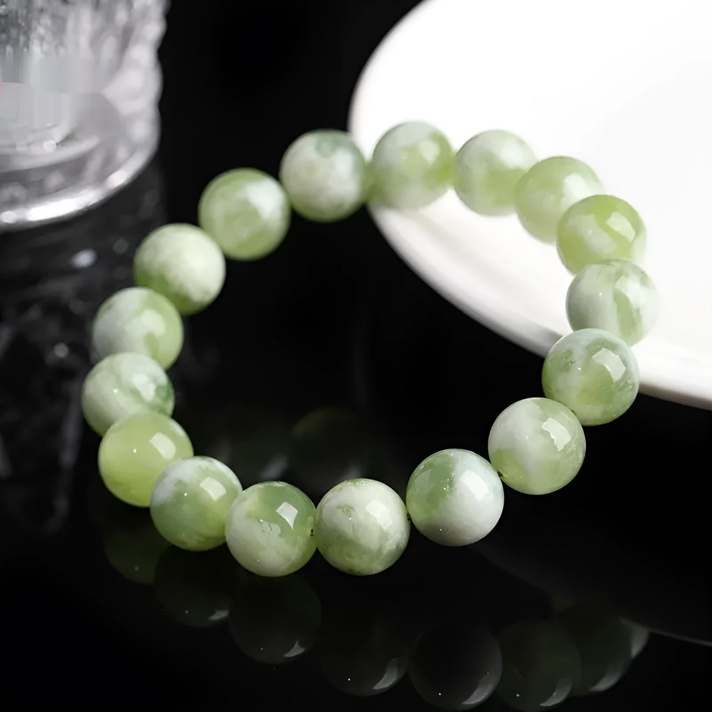 Green milk-in-water Xiuyan jade bracelet with geometric beads on white background
