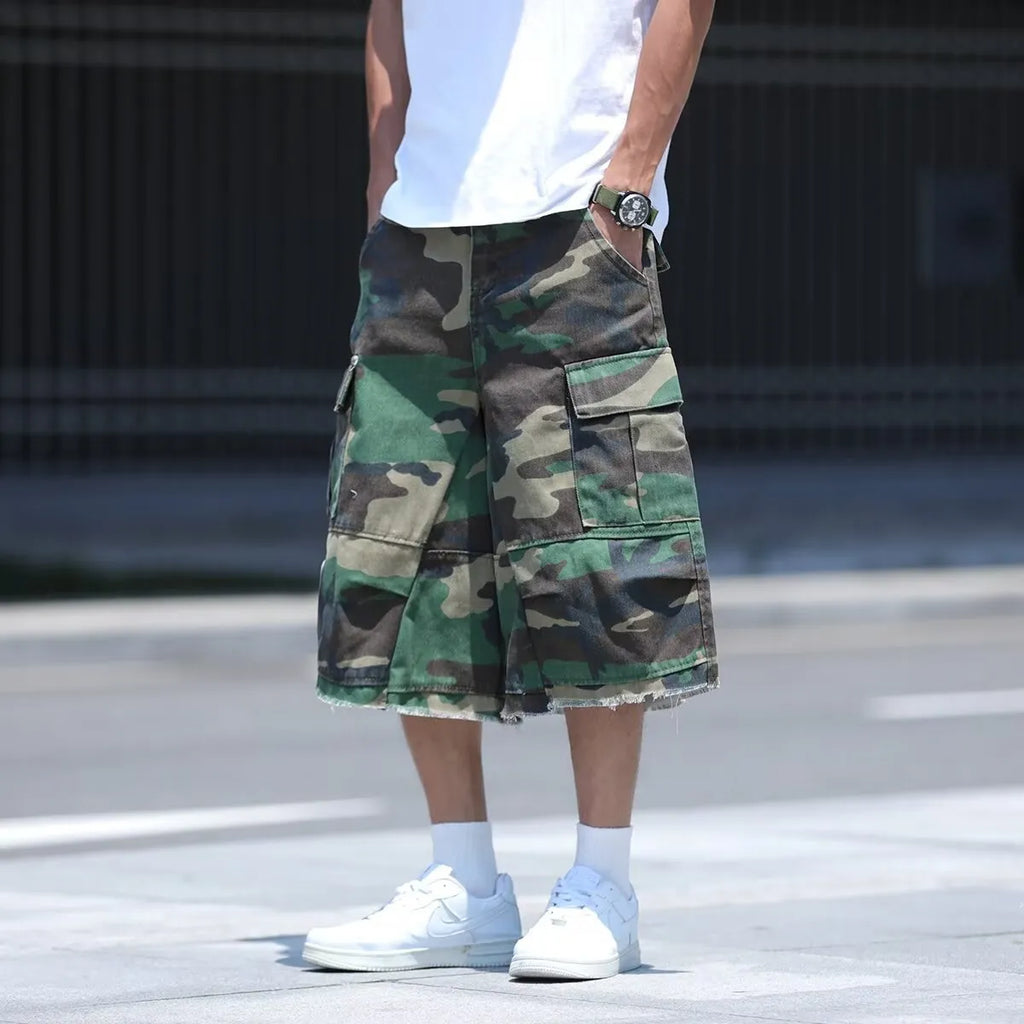 Man wearing loose, cropped camouflage shorts in a khaki colourway, showcasing the summer workwear style.