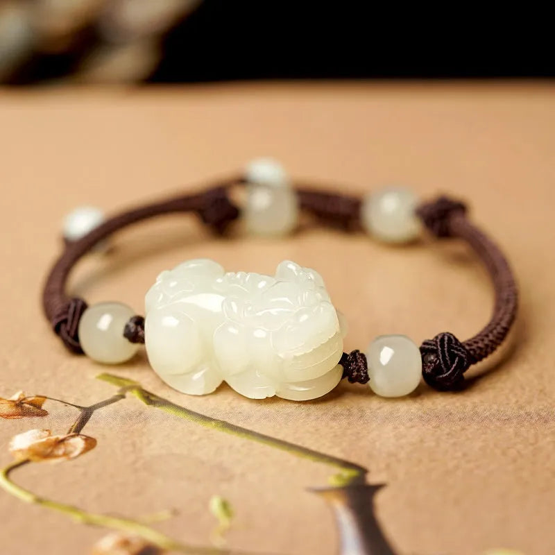 Close-up of a brown and black braided rope bracelet with a central Hetian jade bead on a wrist.