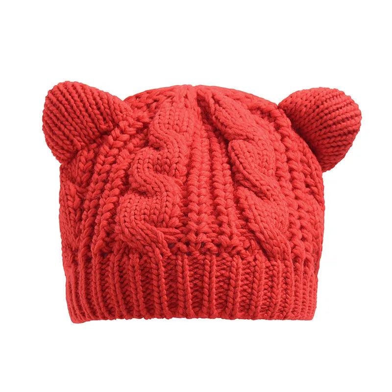 Hand knitted red wool beanie with 3D cat ears on a white background