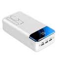 Black and white large 50000mAh portable power bank with multiple USB ports, showing scale next to a smartphone.