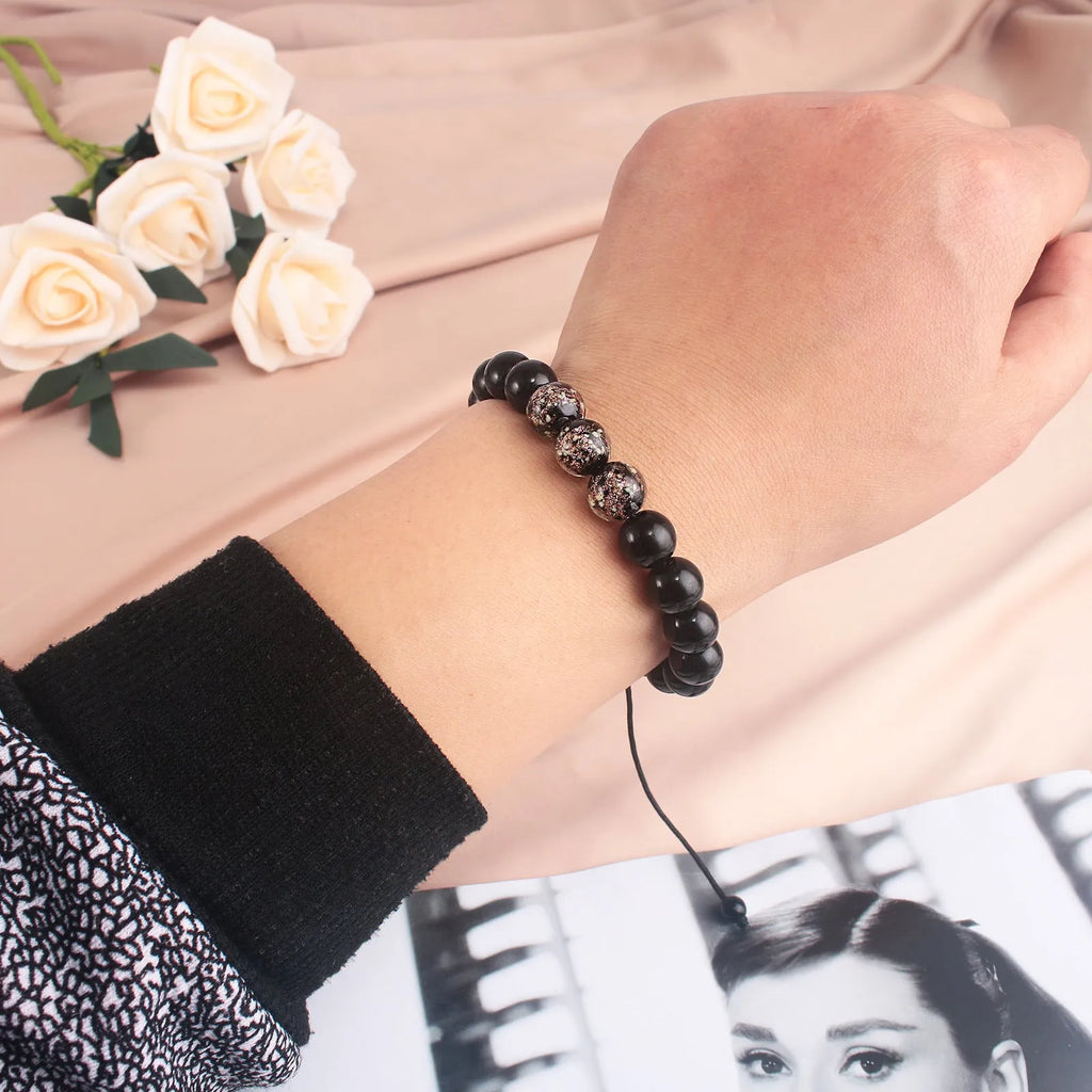 Adjustable luminous glass bead bracelet in geometric shapes on wrist showing elastic cord threading