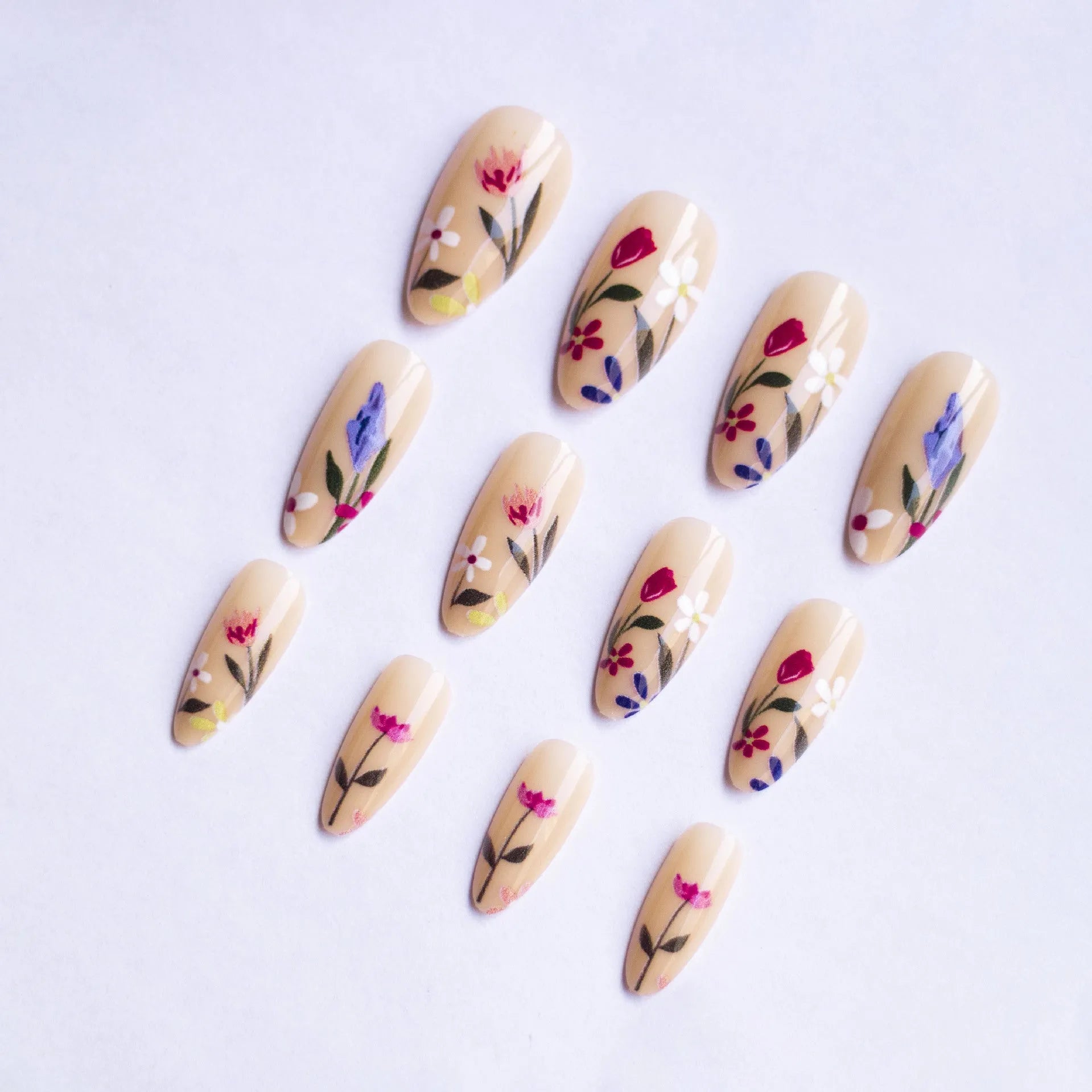 Almond-shaped removable nail art set featuring rose, tulip, and flower patterns on a hand.