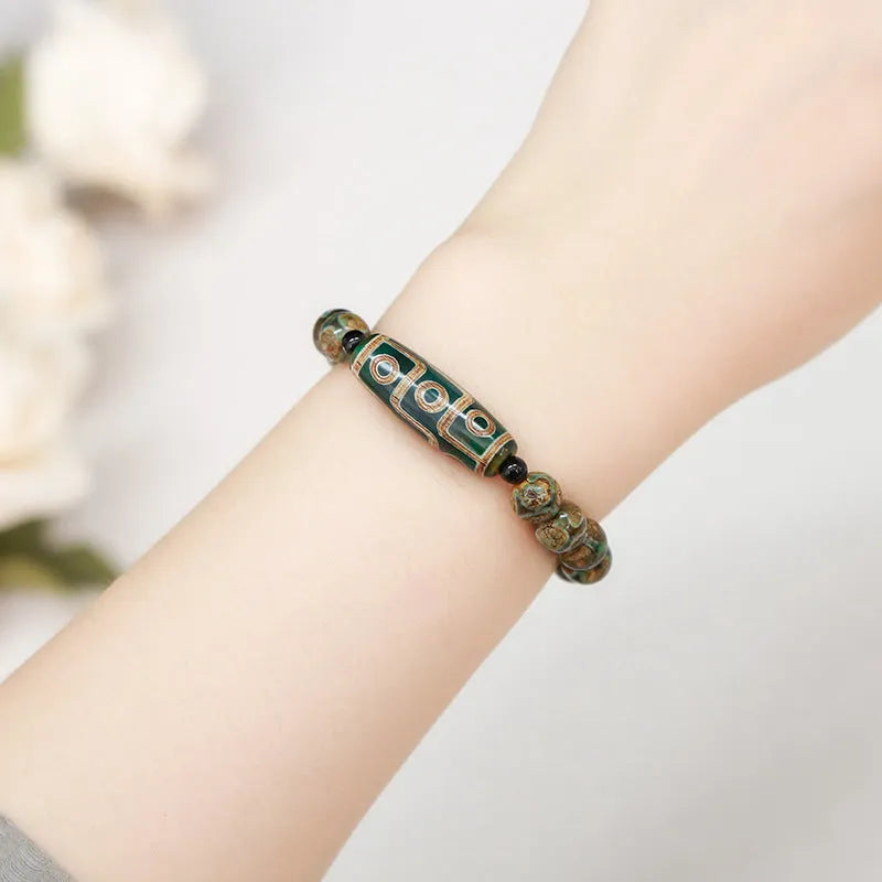 Handmade green dzi bead barrel bracelet with 8mm round geometric beads on a wrist.