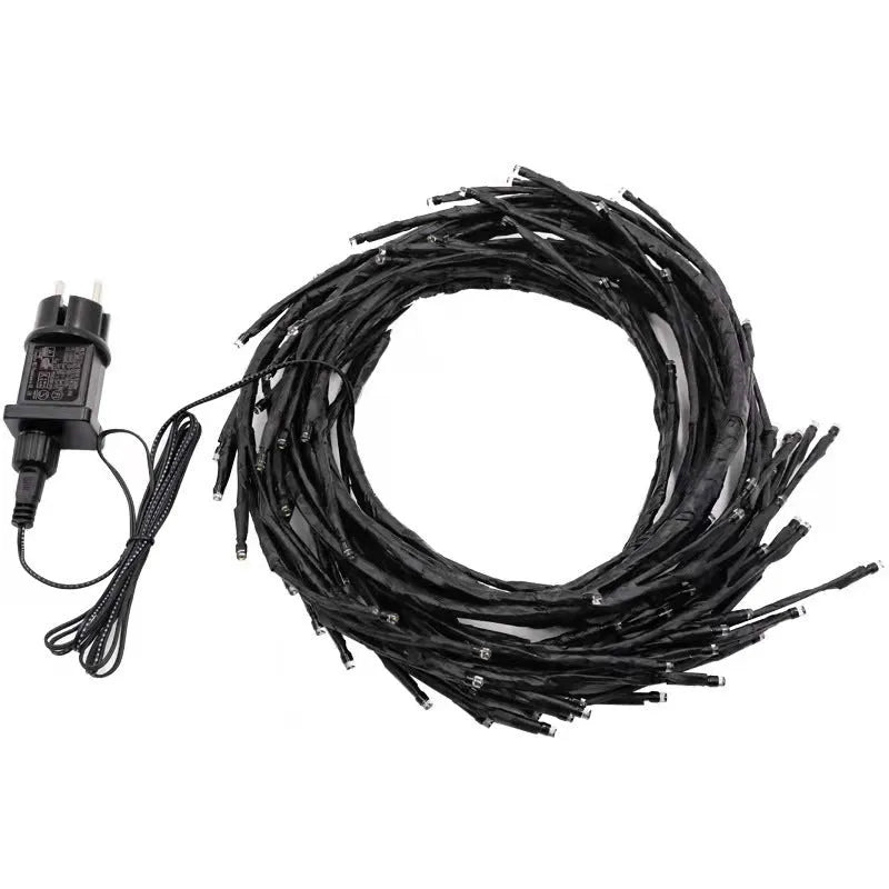 Flexible plastic LED willow vine garland with warm white lights bent into a decorative shape on a wall.