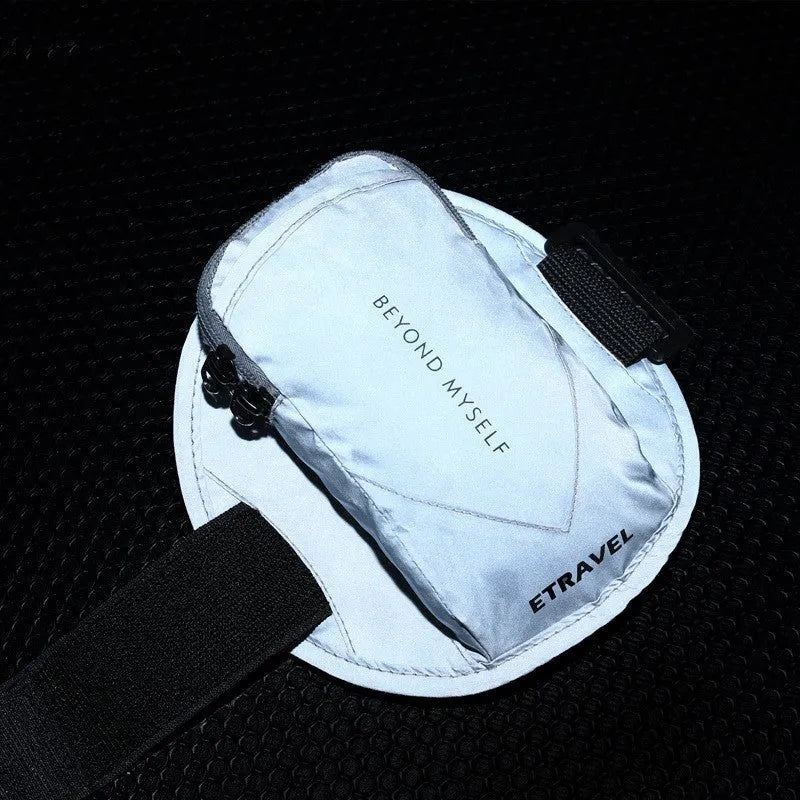 Black reflective running arm bag with adjustable strap, shown on a runner's arm at dusk.