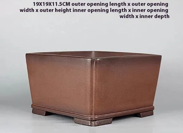 Brown handmade purple clay antique flower pot on a desktop.
