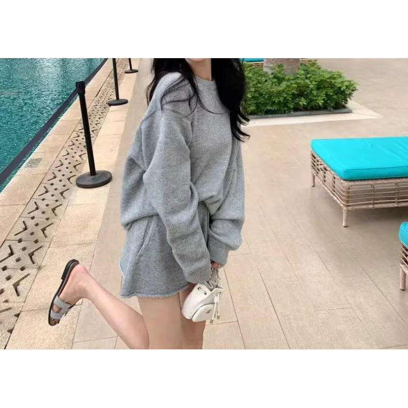 Woman wearing a loose-fit long sleeve knitted sweater and matching high-waisted wide-leg shorts in a neutral colour.