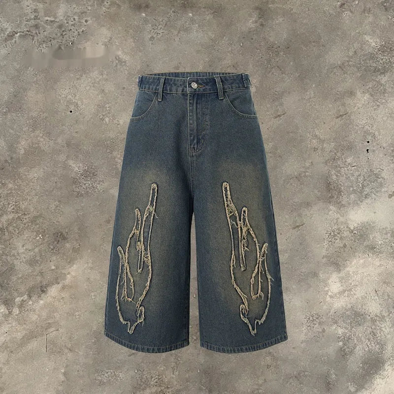 Men's black denim shorts with flame embroidery patch detail on straight leg cropped design