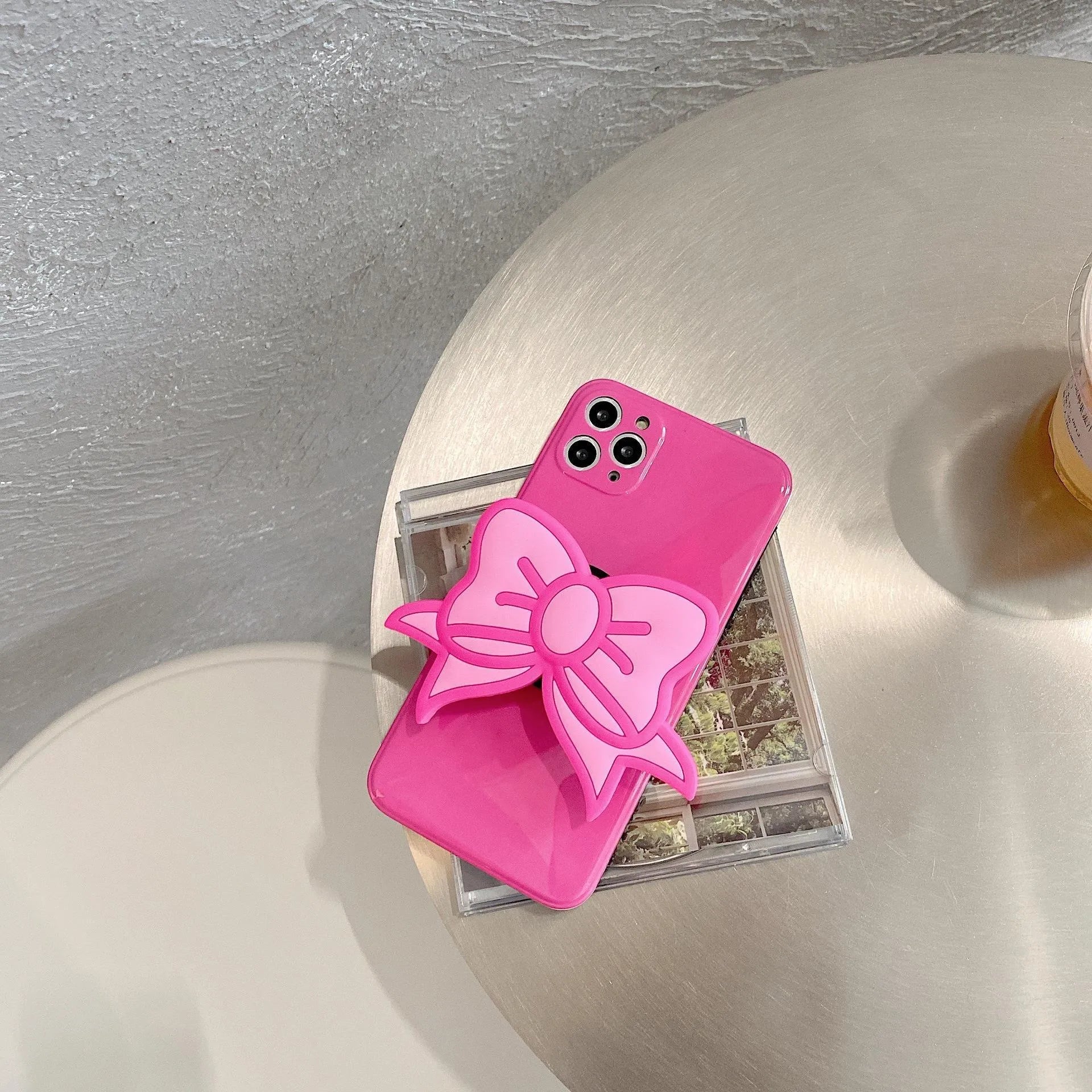 Rose red iPhone case with a large pink bow and a folded-out kickstand on the back.