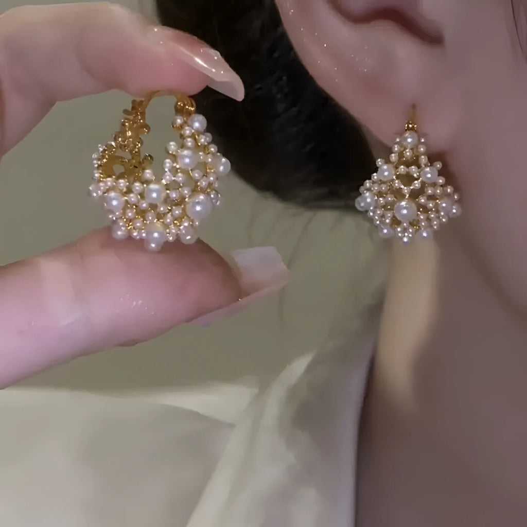A pair of gold-coloured copper flower basket earrings with pearl inlay and small rice-shaped bead details.