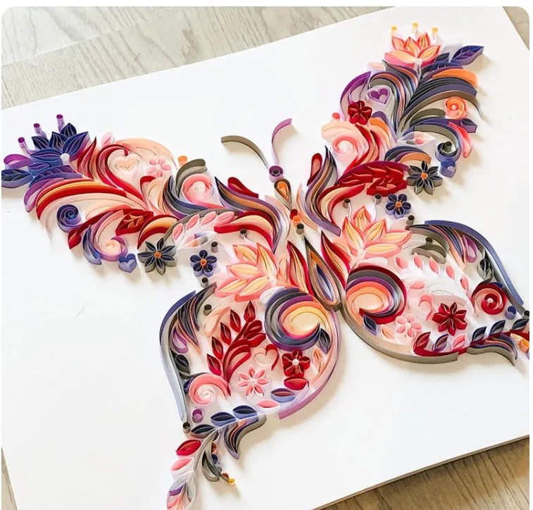 Handmade 20-inch Blue and Pink butterfly quilling paper craft kit with tools on a table
