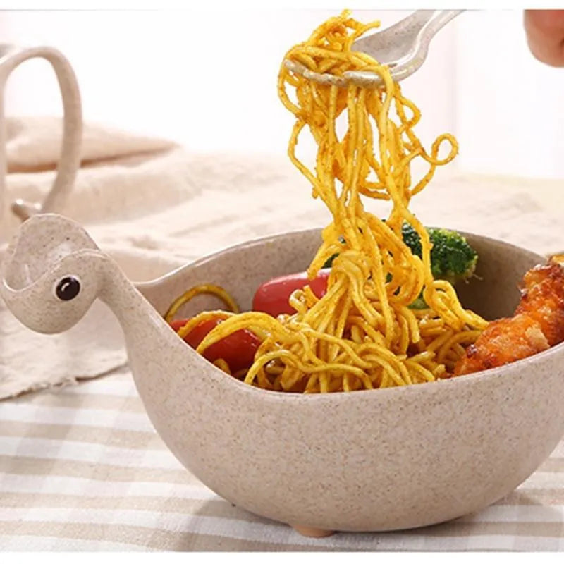 Three wheat straw dinosaur bowls in pink, green, and beige on a kitchen table