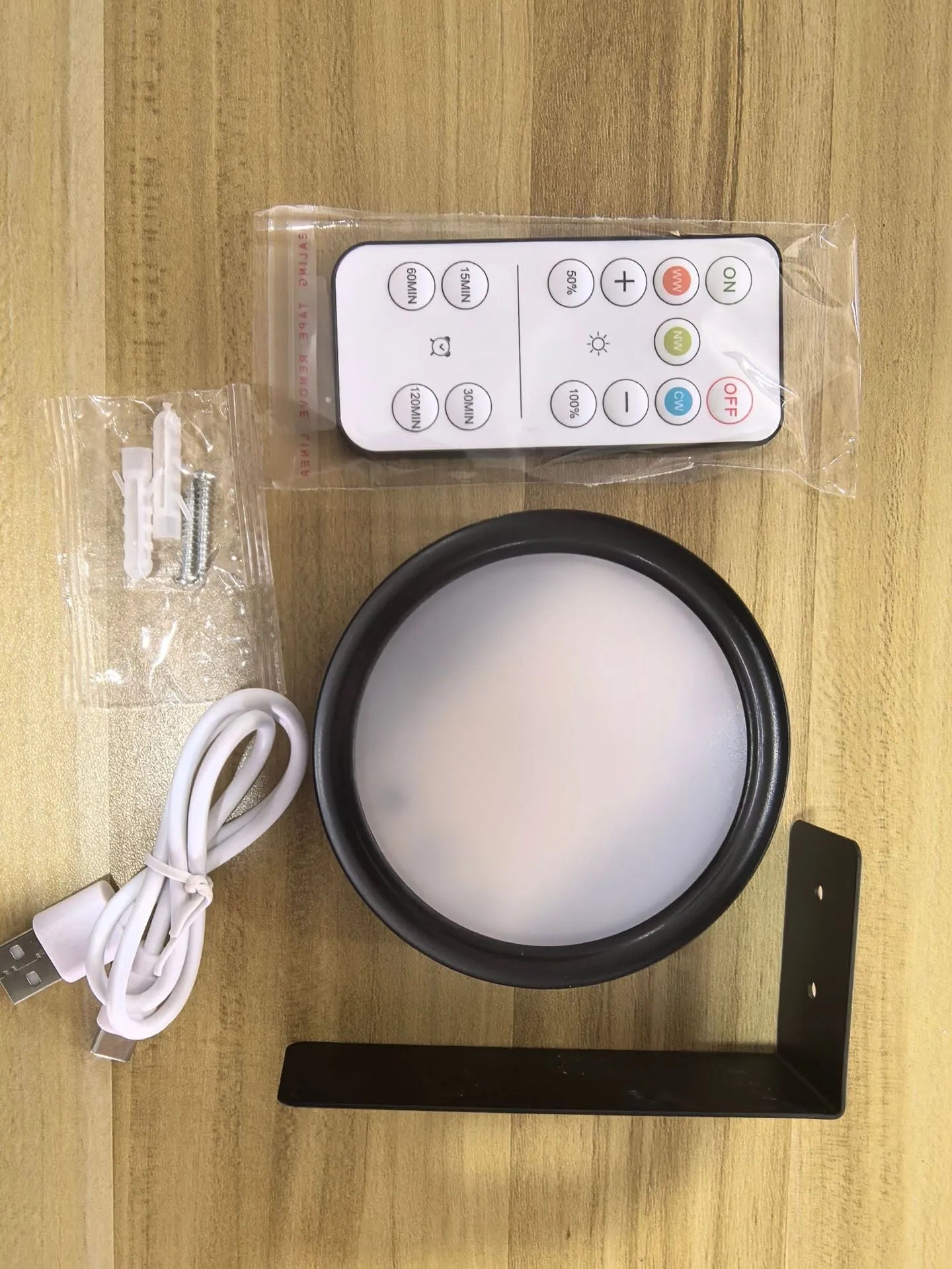 Black magnetic wireless LED lamp with remote control mounted next to a painting on a wall.