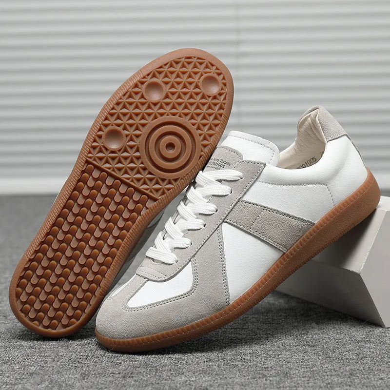 White low-top retro sneakers with round toe and lace-up front on a flat rubber sole.