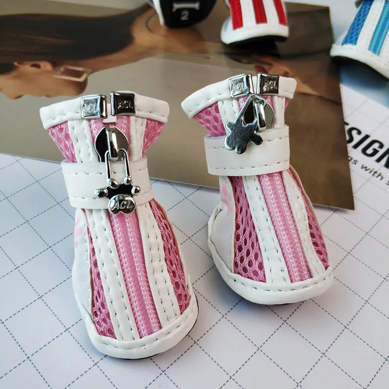Four pairs of blue, pink, and red cloth dog shoes with zip fastenings on a white background.