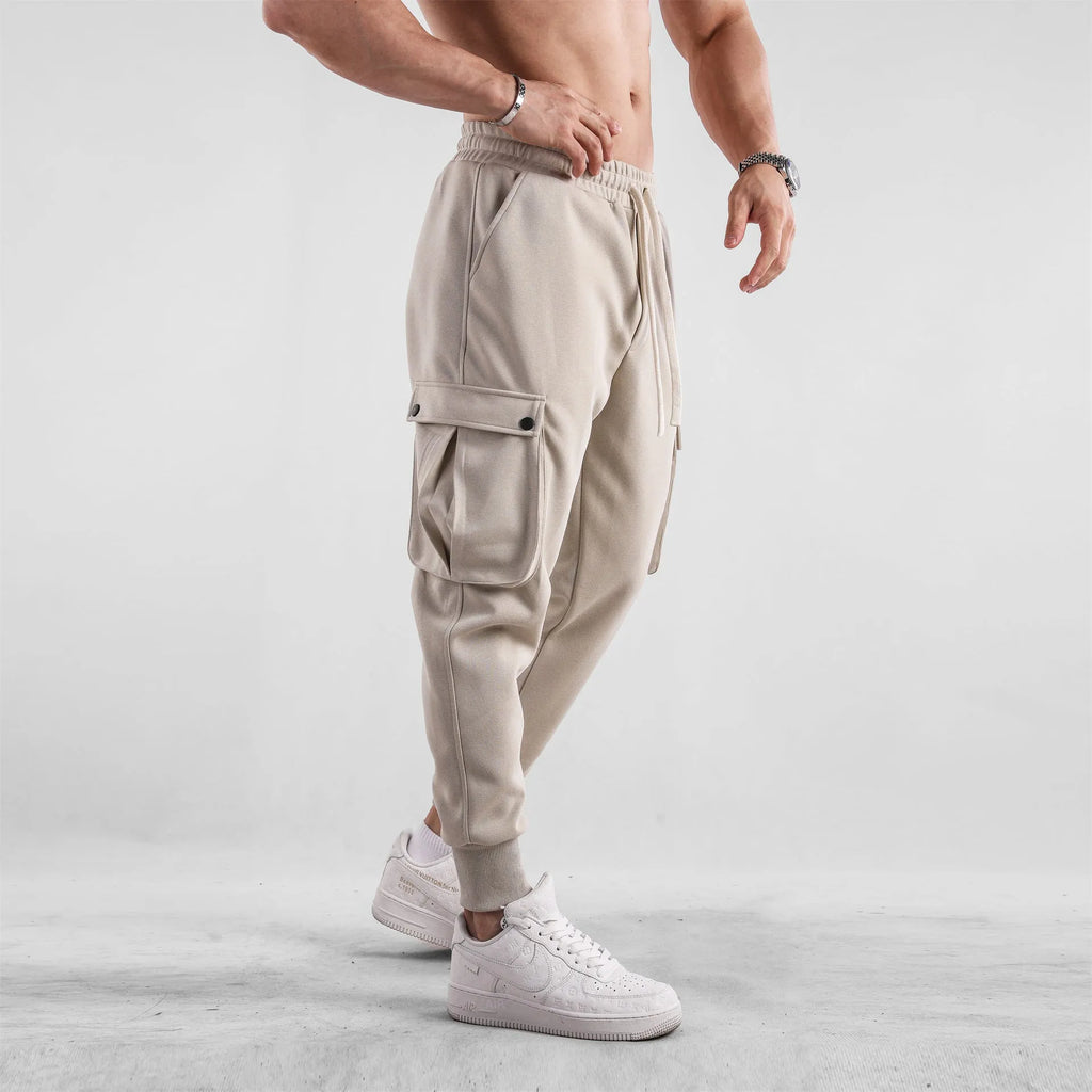 Men's loose-fit apricot coloured cotton sports trousers with an ankle tie and side pockets on a neutral background.