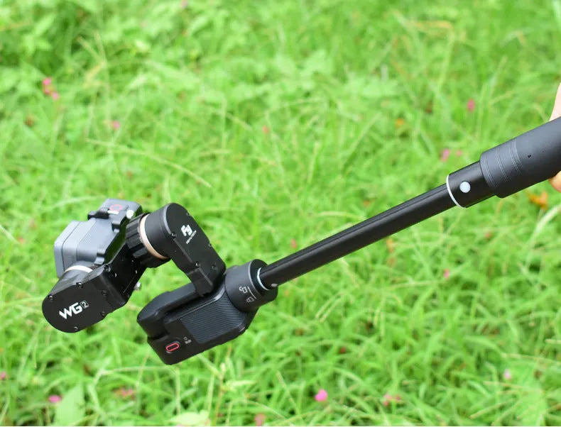 Black retractable selfie stick with extended aluminium pole and Bluetooth remote, holding a smartphone.