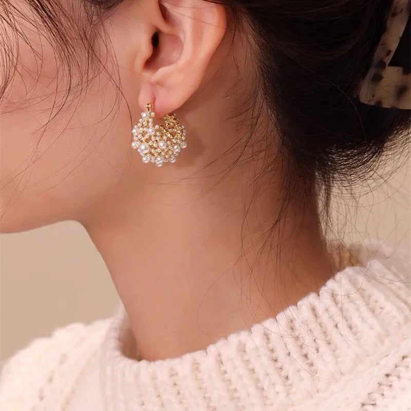 A pair of gold-coloured copper flower basket earrings with pearl inlay and small rice-shaped bead details.