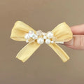 Yellow cloth bow hair clip with rhinestone pearls on duckbill clip mechanism
