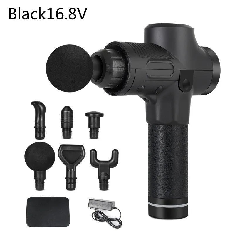 Black electric muscle massage gun with multiple attachment heads on a table.