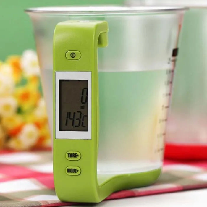 Green digital kitchen scale measuring cup with LCD display in handle on kitchen counter