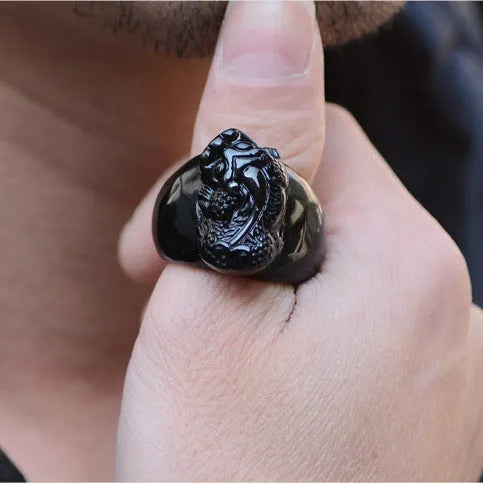 Men's black obsidian Pixiu thumb ring with gold sheen on an alloy band, showing side profile.