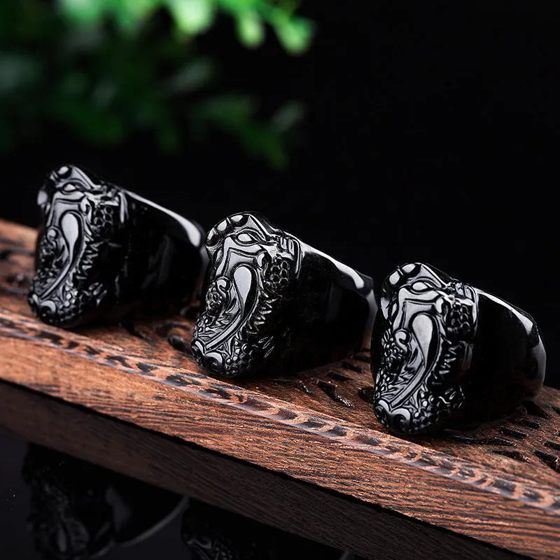 Men's black obsidian Pixiu thumb ring with gold sheen on an alloy band, showing side profile.