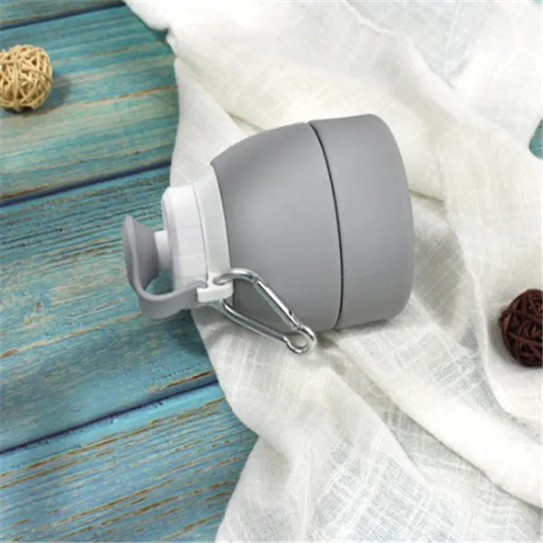 Blue silicone folding water bottle shown expanded and collapsed with measurement scale