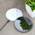 Black aluminium alloy 15W Qi fast wireless charging pad on a wooden desk