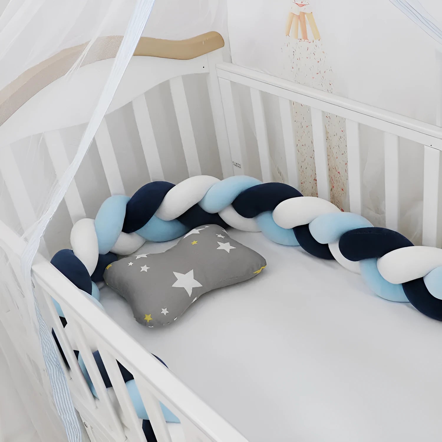 Close-up of a grey braid knot pillow cushion cot bumper fitted around white crib rails.