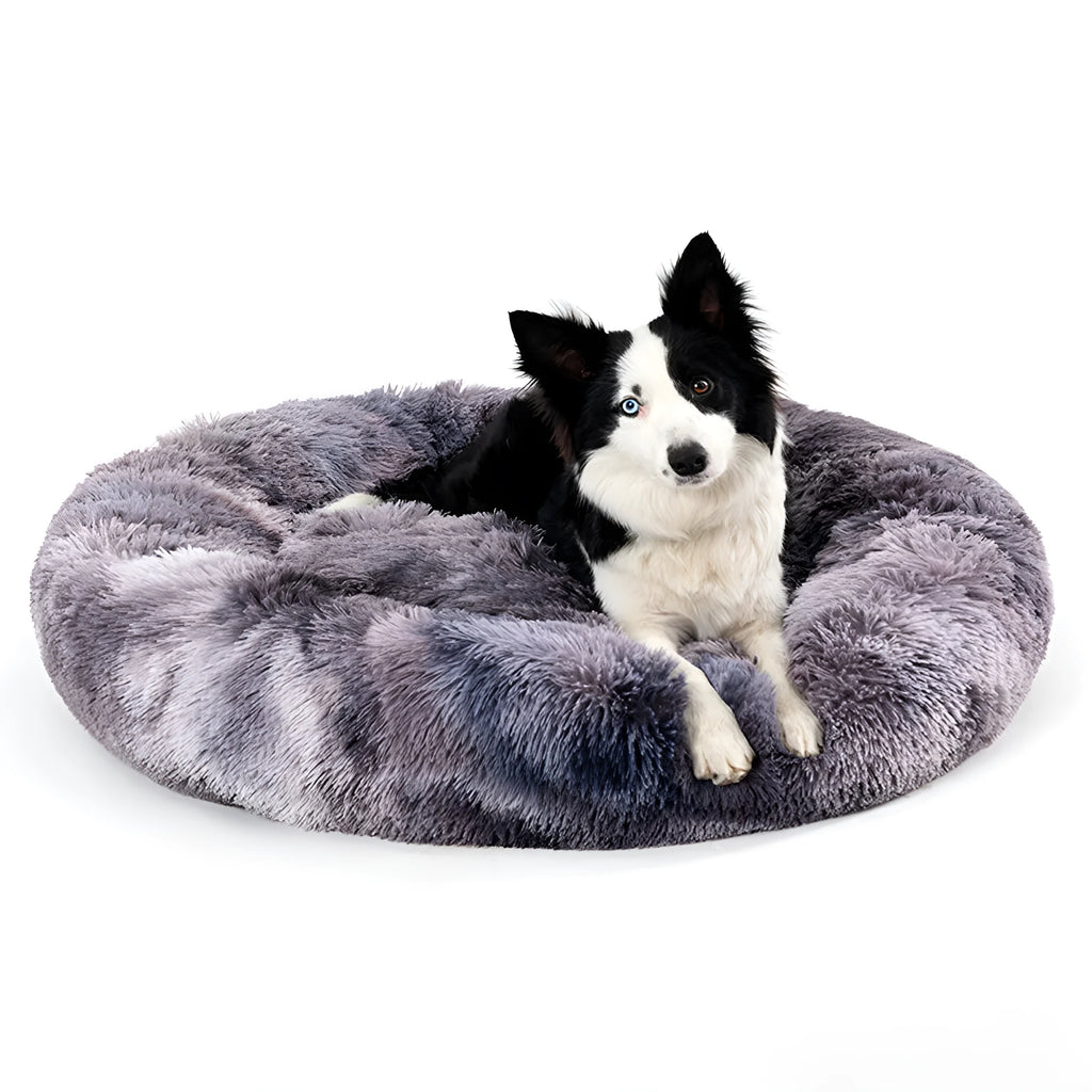 Fluffy grey donut-shaped dog bed with high plush sides on a wooden floor.