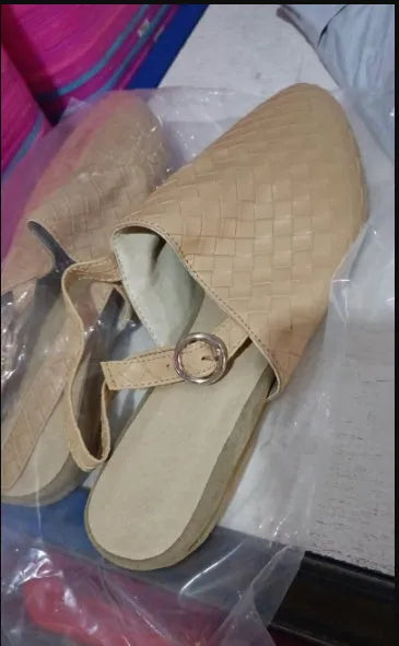 A pair of black baotou flat sandals with a buckle fastening and a pointed toe on a rubber sole.