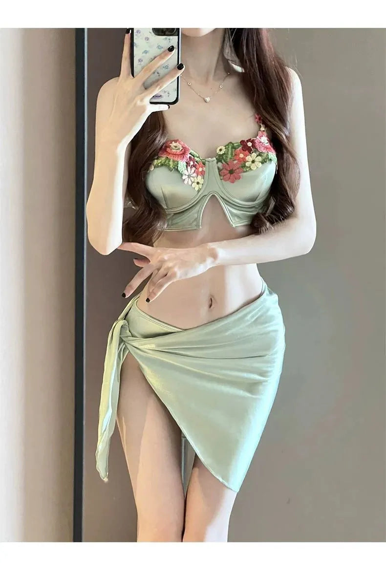 Green women's three-piece bikini set showing sleeveless triangle top, briefs, and a skirt on a mannequin.