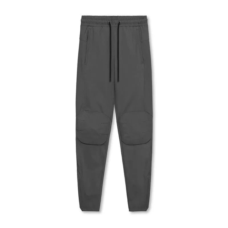 Man wearing dark grey loose-fit ankle-tied fitness trousers made from quick-drying polyester.