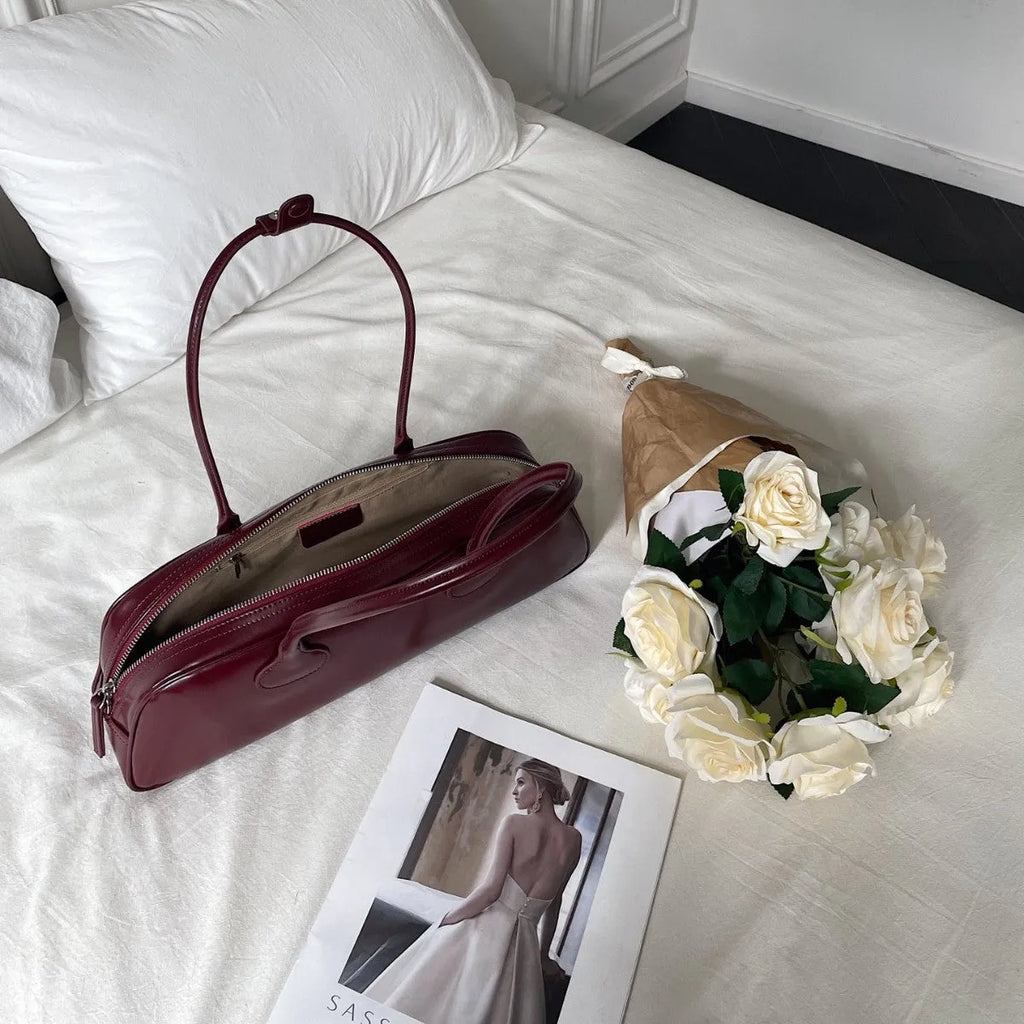 Women's solid colour genuine cowhide leather oval single-shoulder bag in brown with visible sewing thread detail.