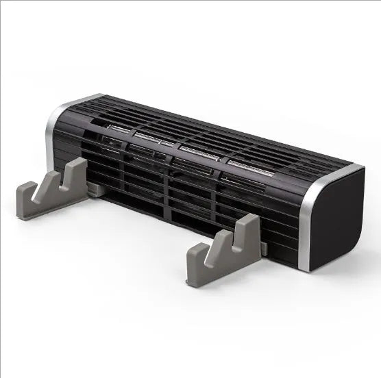 Black notebook cooler with dual fans and USB cable on a wooden desk next to a laptop