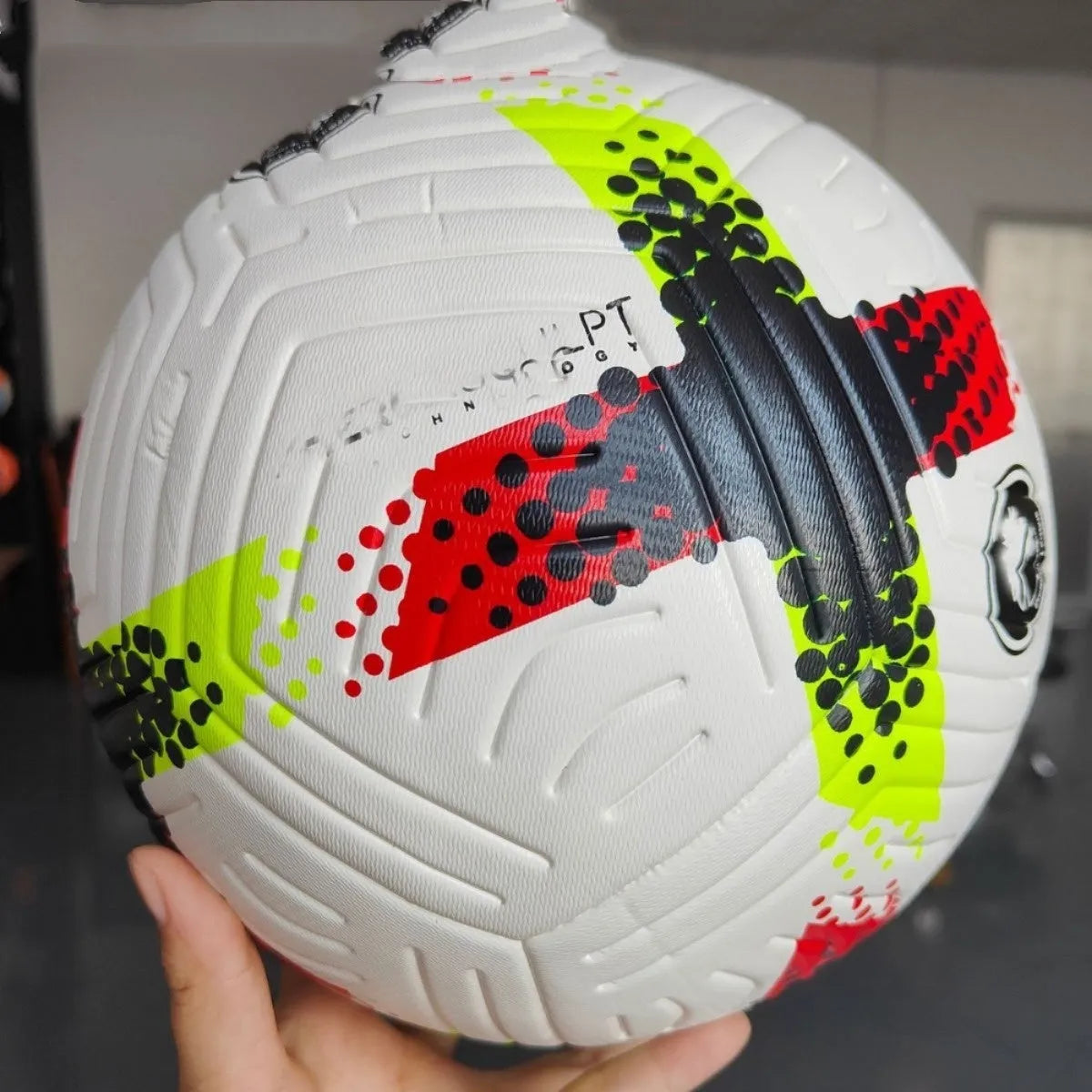 Fluorescent green Size 5 football on a field, showing seamless PU construction.