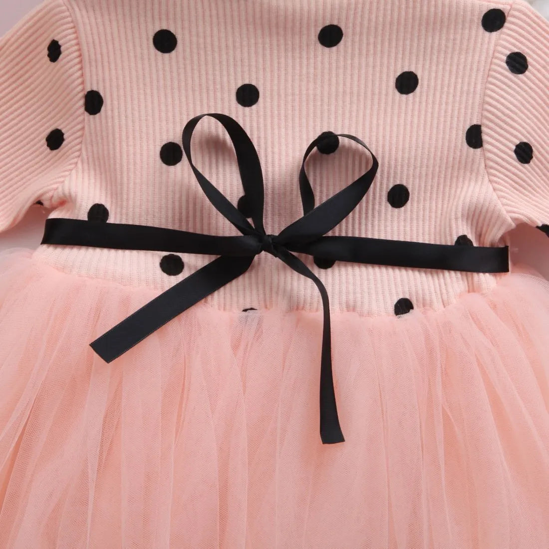 Baby girl wearing a long sleeve black tutu lace dress for a first birthday party.